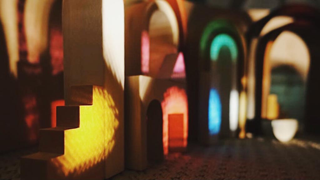 Wooden block houses lit by coloured light from stained-glass windows