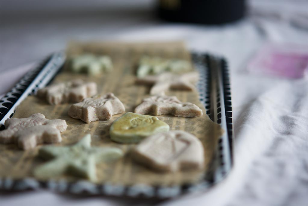 Hands cutting shapes from rolled salt dough on a wooden board